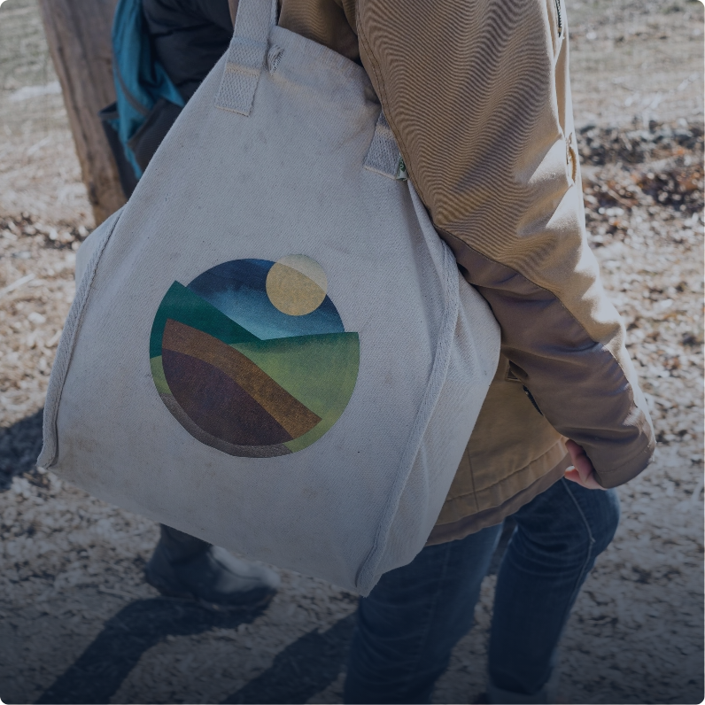 a close up shot of someone carrying a hawthorne valley tote bag. it is a close up of the bag which has only the hawthorne valley logo
