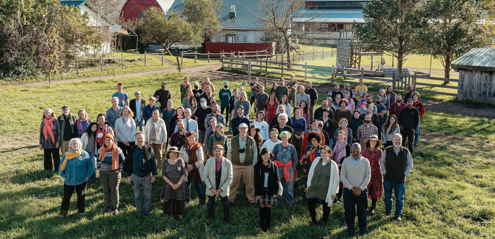 Hawthorne Valley staff in a field with the play yard, creamery, and dining hall behind them