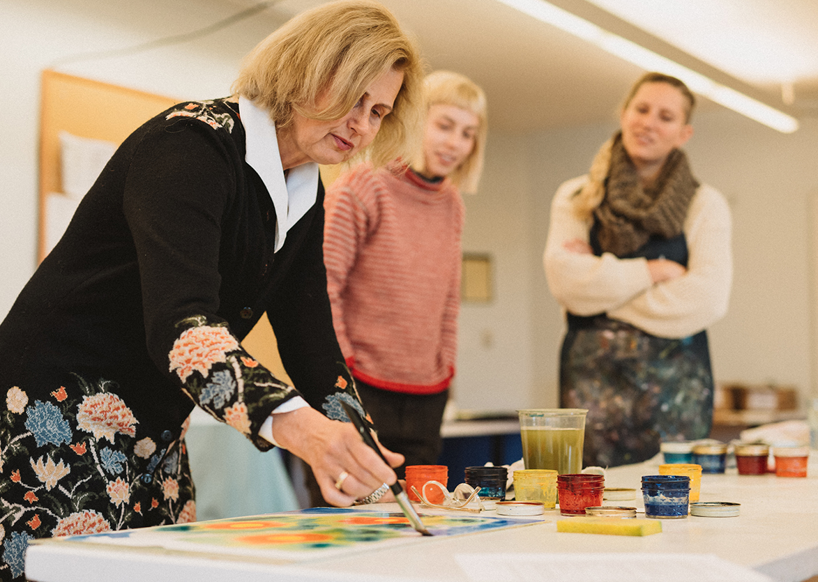 Photo of Martina Muller showing two Alkion center students how to paint a project.